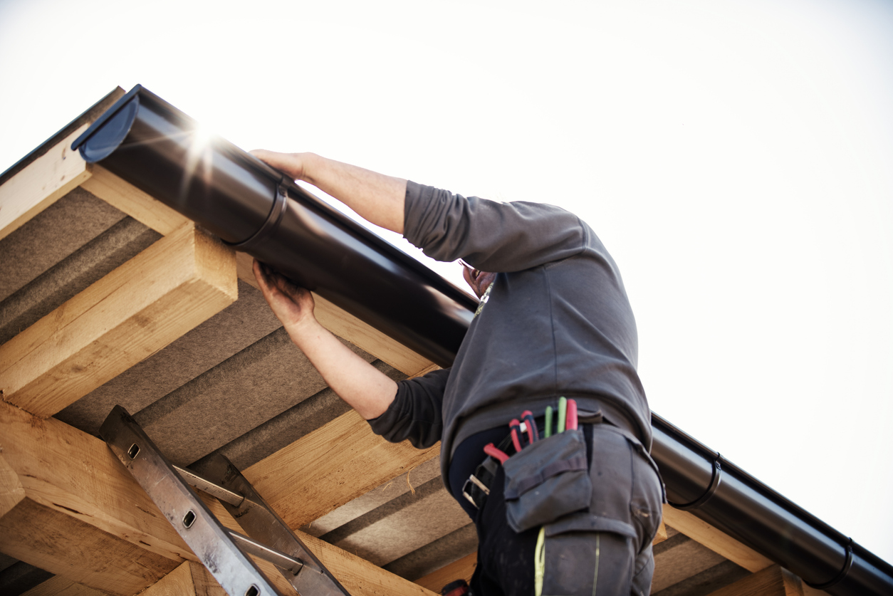 Worker On Roof Installing Gutter